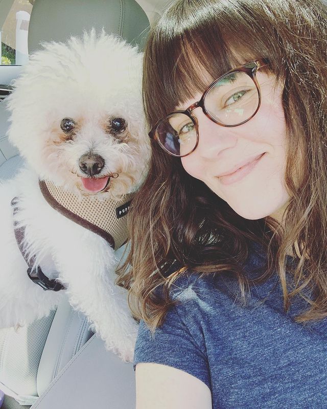 Katie Featherston in a blue t-shirt posing with her pet dog Harvey.